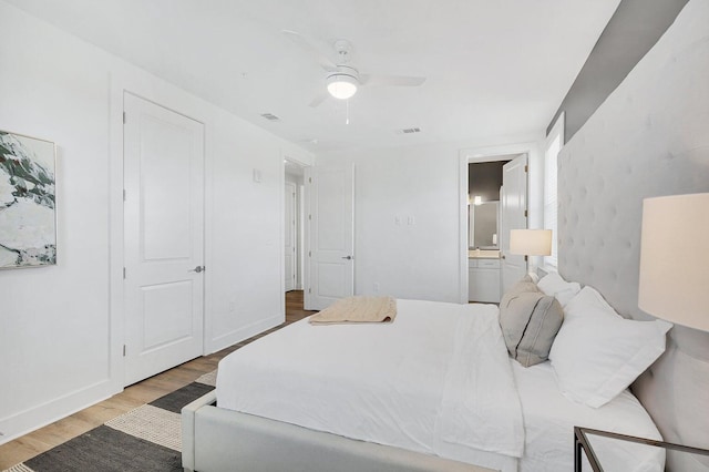 bedroom with visible vents, baseboards, ensuite bath, and wood finished floors