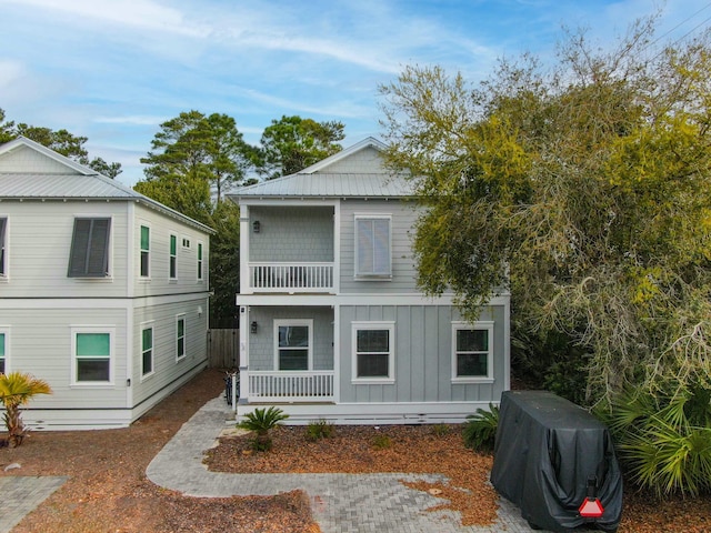 back of house featuring a balcony, board and batten siding, and covered porch