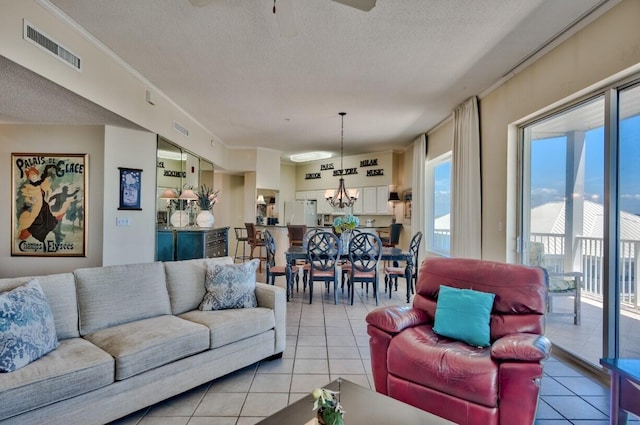 living area featuring visible vents, a textured ceiling, light tile patterned flooring, and ceiling fan with notable chandelier