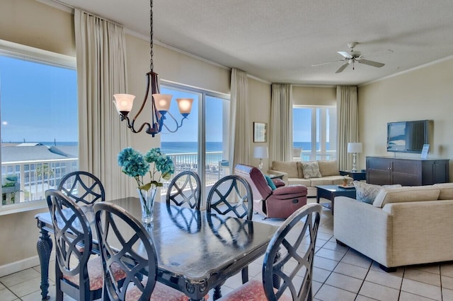 dining space featuring crown molding, baseboards, light tile patterned floors, ceiling fan with notable chandelier, and a textured ceiling