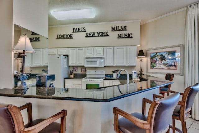 kitchen with a kitchen bar, white appliances, and ornamental molding