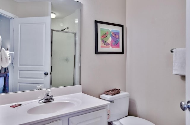 bathroom featuring vanity, a shower stall, and toilet