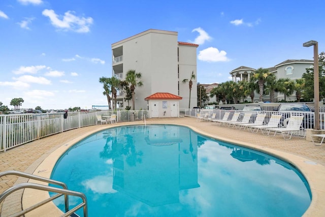 community pool with a patio and fence