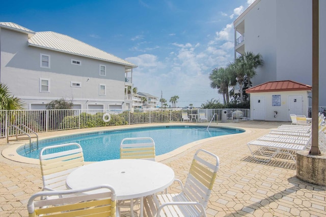 community pool with a patio and fence