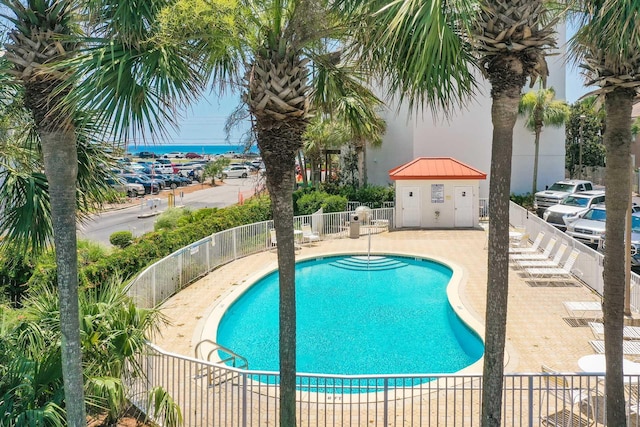 community pool featuring a storage unit, an outdoor structure, a patio, and fence