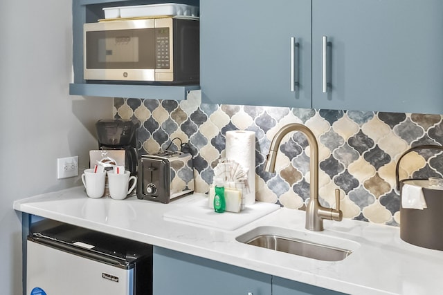 kitchen with stainless steel microwave, light countertops, backsplash, and a sink