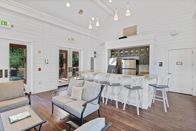 living room featuring beamed ceiling, high vaulted ceiling, dark wood finished floors, french doors, and wooden walls