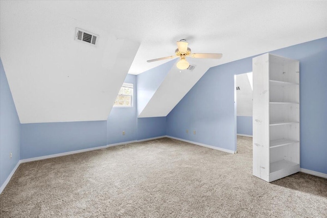 additional living space featuring visible vents, baseboards, carpet flooring, lofted ceiling, and ceiling fan