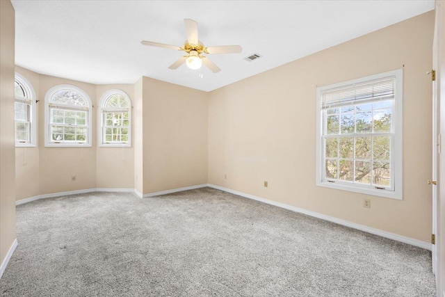 carpeted empty room with a ceiling fan, visible vents, and baseboards