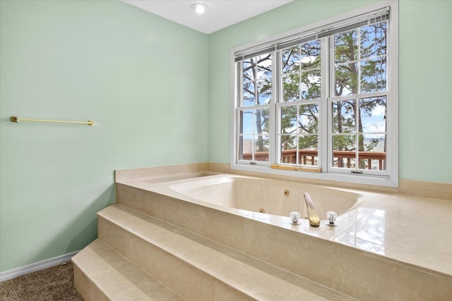 bathroom with a tub with jets and baseboards