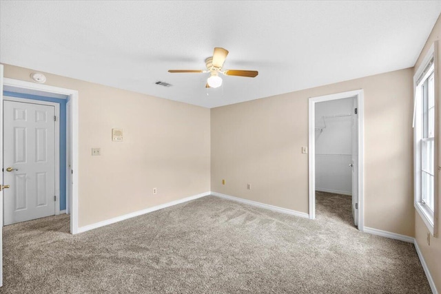 unfurnished bedroom with baseboards, visible vents, carpet floors, a spacious closet, and a closet