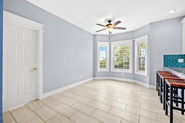 spare room featuring a ceiling fan and baseboards