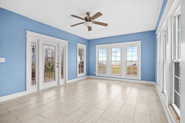 foyer entrance featuring baseboards and ceiling fan