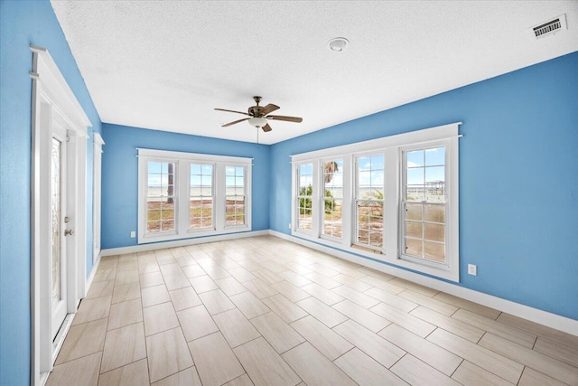 unfurnished room featuring visible vents, baseboards, a textured ceiling, and ceiling fan