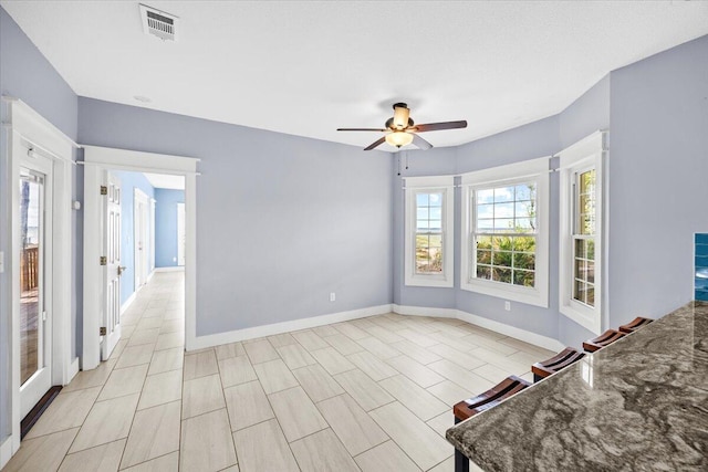 interior space featuring visible vents, baseboards, and ceiling fan