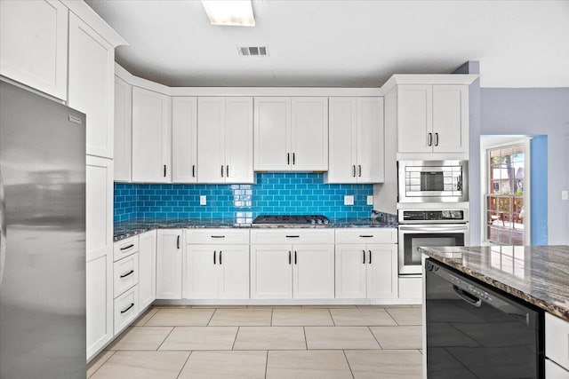 kitchen featuring white cabinetry, dark stone counters, tasteful backsplash, and appliances with stainless steel finishes