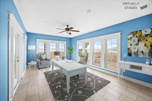 office featuring baseboards, visible vents, a textured ceiling, and a ceiling fan