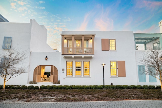 exterior space featuring stucco siding, a pergola, and a balcony