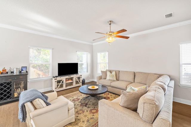 living room with visible vents, a healthy amount of sunlight, wood finished floors, and ornamental molding