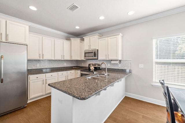 kitchen featuring ornamental molding, wood finished floors, visible vents, and stainless steel appliances