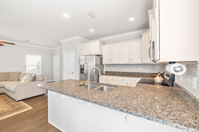 kitchen with visible vents, a peninsula, a sink, electric stove, and stainless steel fridge