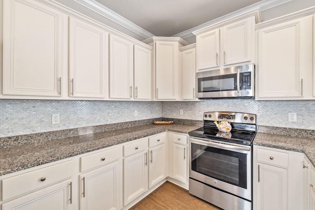 kitchen featuring light wood finished floors, tasteful backsplash, crown molding, dark stone counters, and appliances with stainless steel finishes