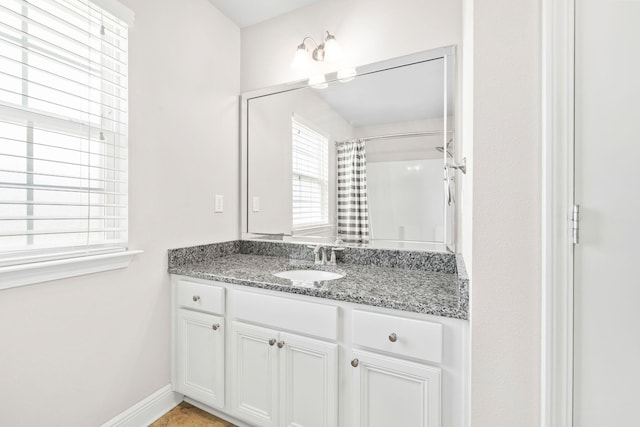 bathroom featuring a shower with shower curtain, baseboards, and vanity