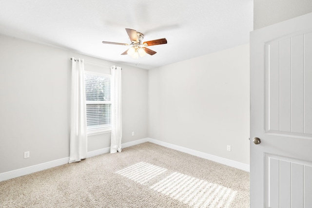 carpeted spare room with a ceiling fan and baseboards