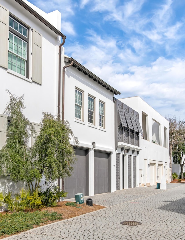 view of front of house featuring stucco siding, decorative driveway, and a garage