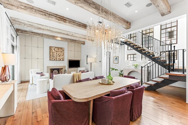 dining room with visible vents, light wood-style flooring, a fireplace, a chandelier, and stairs