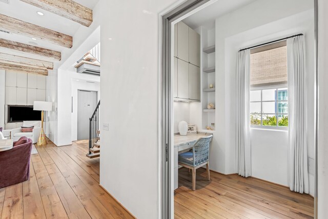 hall with stairs, beamed ceiling, built in features, and light wood-style floors