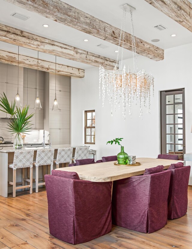 living area with recessed lighting, visible vents, beam ceiling, and wood finished floors