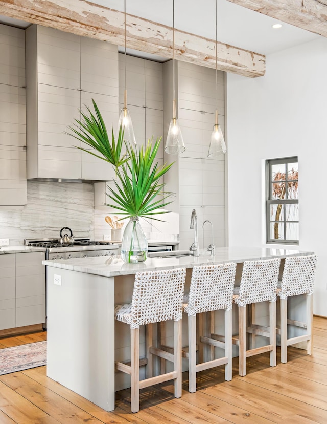 kitchen with tasteful backsplash, a breakfast bar area, modern cabinets, and light wood-style floors