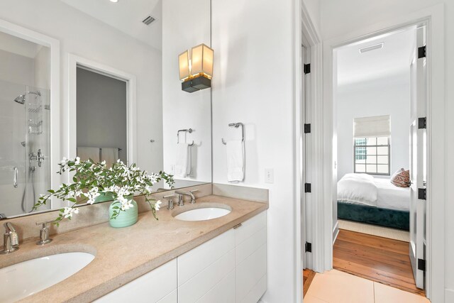 full bathroom with a sink, visible vents, connected bathroom, and a shower stall