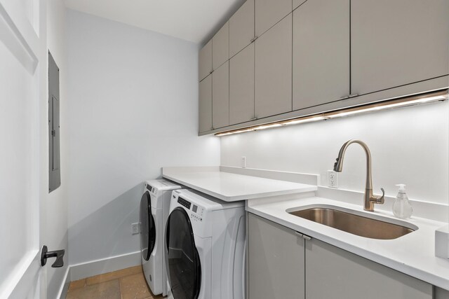 clothes washing area featuring baseboards, washer and clothes dryer, stone finish floor, cabinet space, and a sink