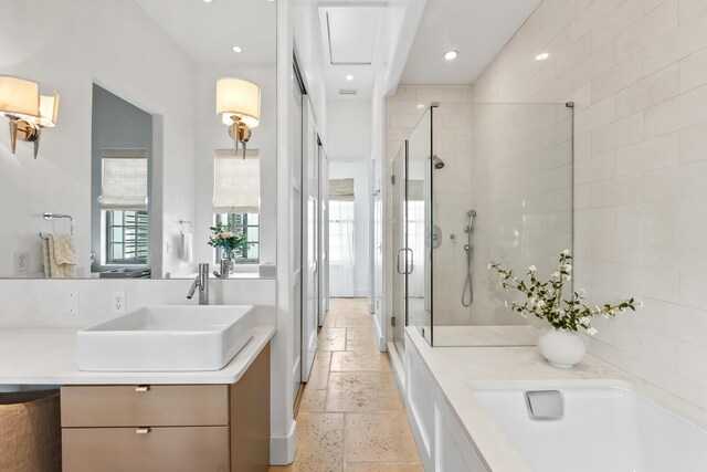 bathroom with stone tile floors, double vanity, recessed lighting, a sink, and a shower stall