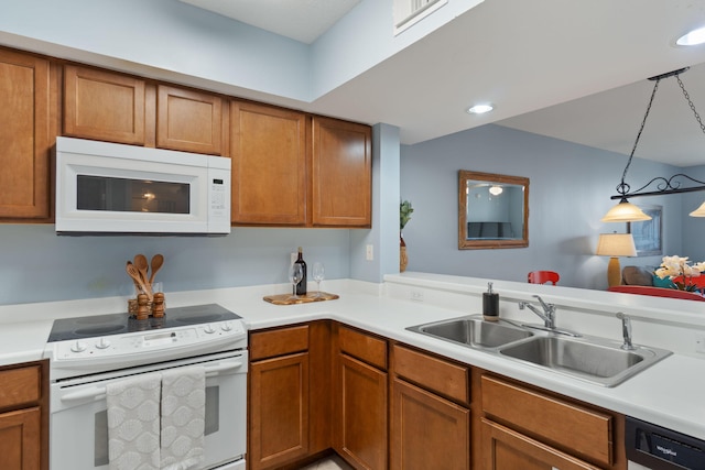kitchen with white appliances, brown cabinetry, visible vents, and a sink