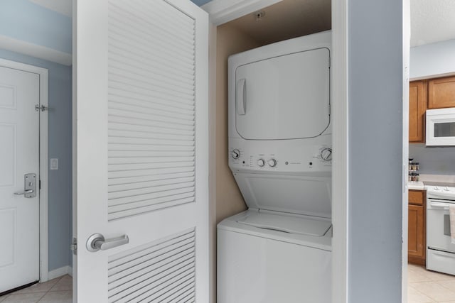 laundry area with laundry area, stacked washer and dryer, and light tile patterned floors