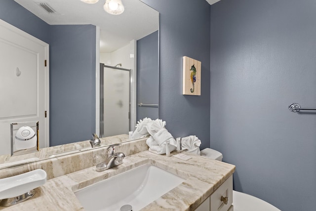 full bathroom with vanity, a shower stall, toilet, and visible vents