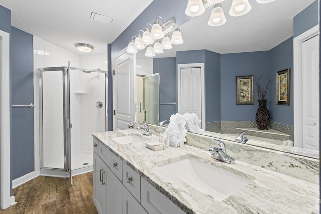 bathroom featuring a sink, double vanity, wood finished floors, and a shower stall