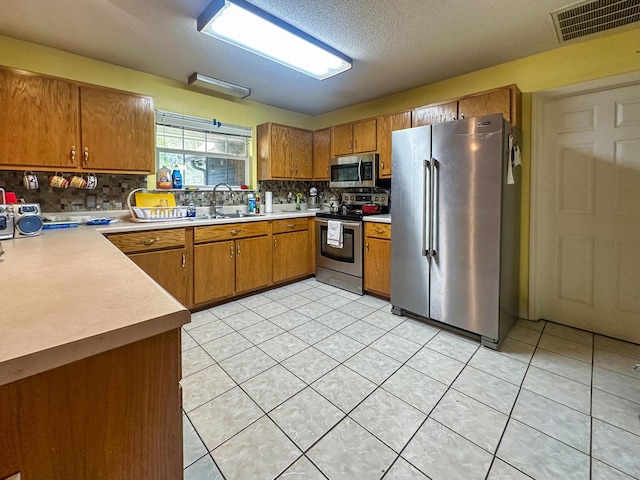 kitchen featuring stainless steel appliances, brown cabinets, visible vents, and light countertops