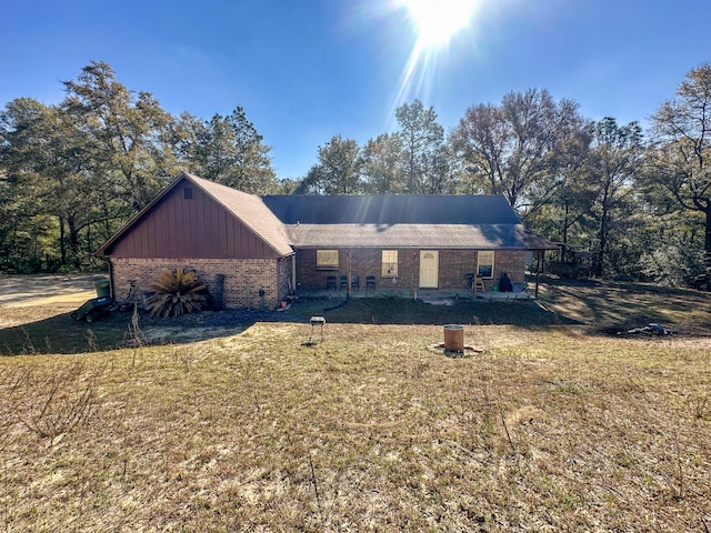 view of front of property featuring board and batten siding, a front yard, and brick siding