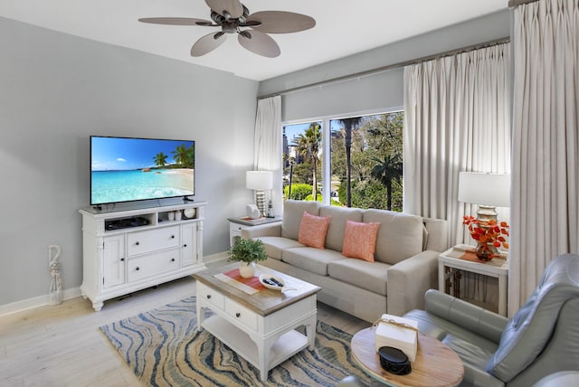 living room featuring light wood-style flooring, baseboards, and ceiling fan