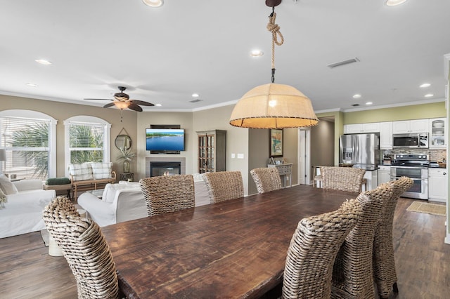 dining area with dark wood-type flooring, ornamental molding, recessed lighting, a fireplace, and a ceiling fan