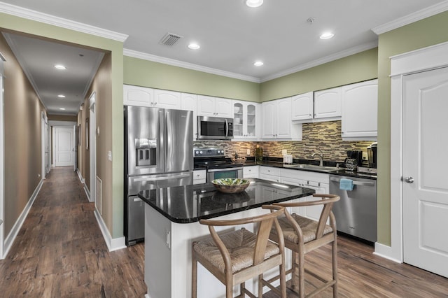 kitchen with visible vents, ornamental molding, dark wood-style floors, stainless steel appliances, and a sink