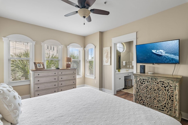 bedroom with dark wood finished floors, ceiling fan, baseboards, and connected bathroom