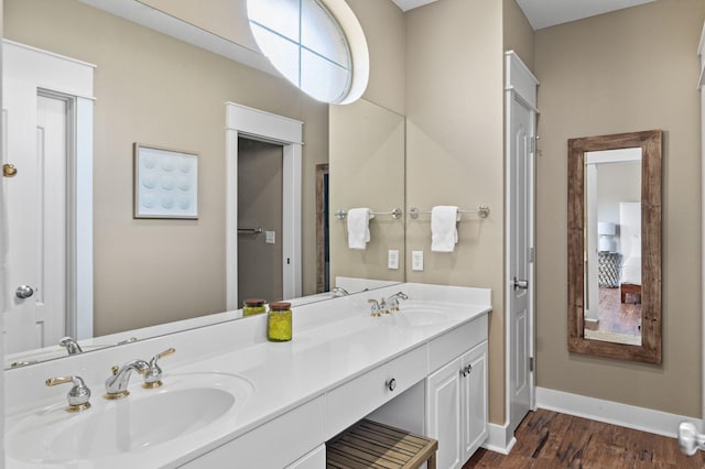 full bathroom featuring double vanity, wood finished floors, baseboards, and a sink