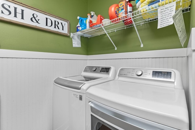 laundry area with laundry area, washing machine and dryer, and a wainscoted wall