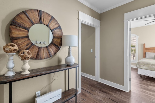 hall with wood finished floors, baseboards, and ornamental molding