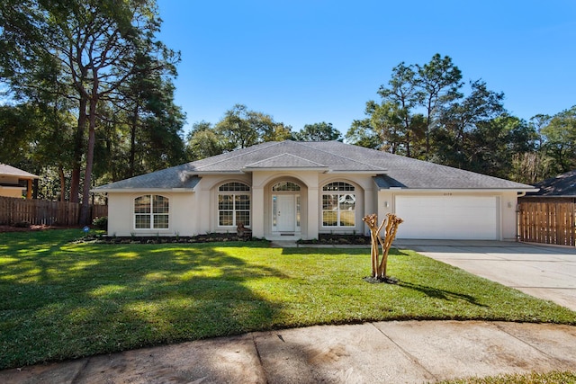 ranch-style house featuring a front yard, an attached garage, fence, and driveway